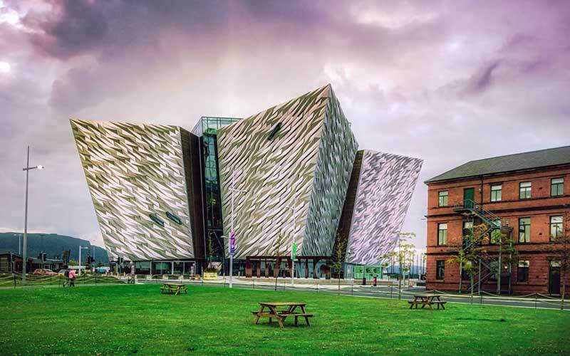 Bangunan Titanic Belfast dengan bangunan Harland dan Wolff lama (di mana Titanic dirancang) ketika matahari terbenam pada hari pertama musim panas