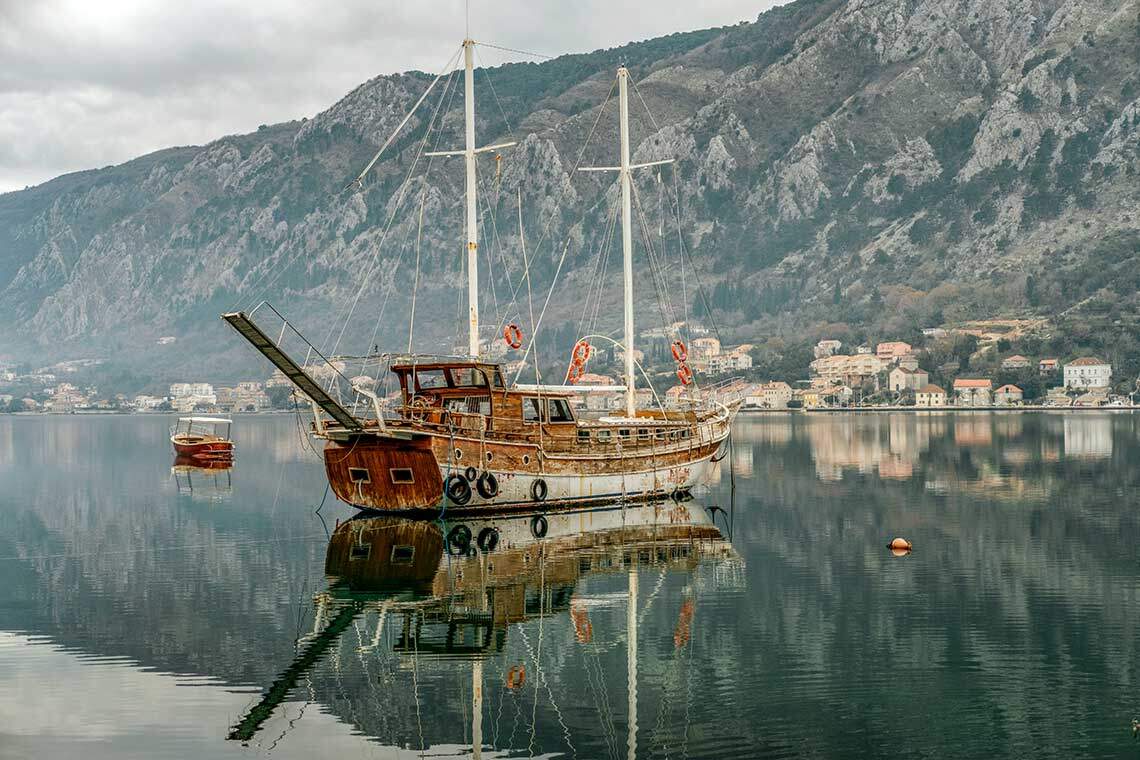 Kapal kuno di teluk Laut Adriatik dengan gunung di Montenegro, Kotor