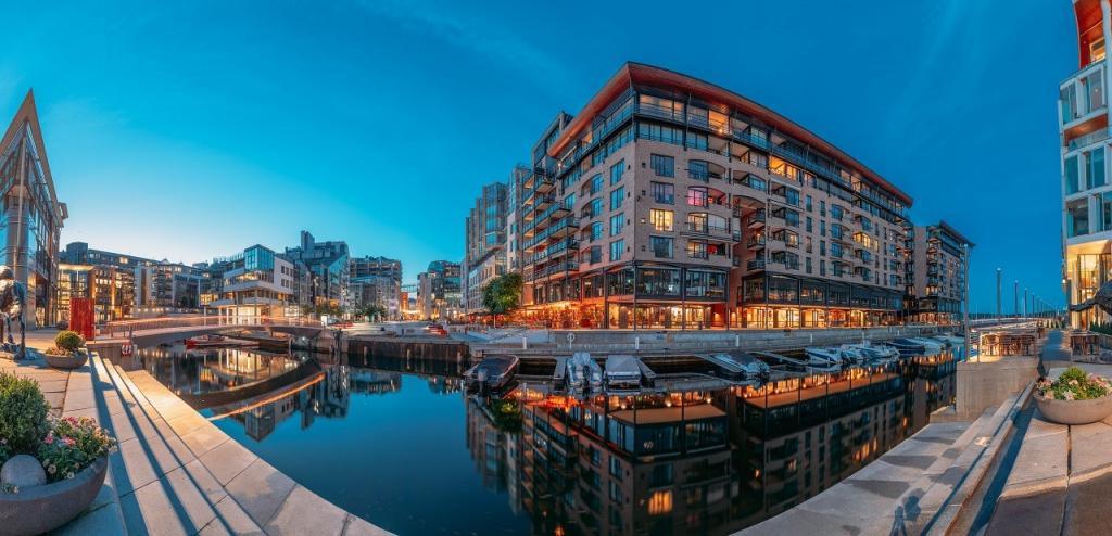 Oslo, Norway. Night Embankment And Residential Multi-storey Houses In Aker Brygge District. Summer Evening. Residential Area Reflected In Waters. Famous And Popular Place. Panorama, Panoramic View