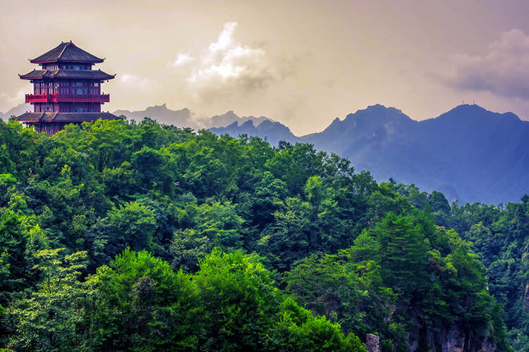 Traditional chinese architecture pagoda temple building on top of a mountain peak overlooking the stunning rock pillars of the Tianzi mountain range, Avatar mountains nature park, Zhangjiajie, China