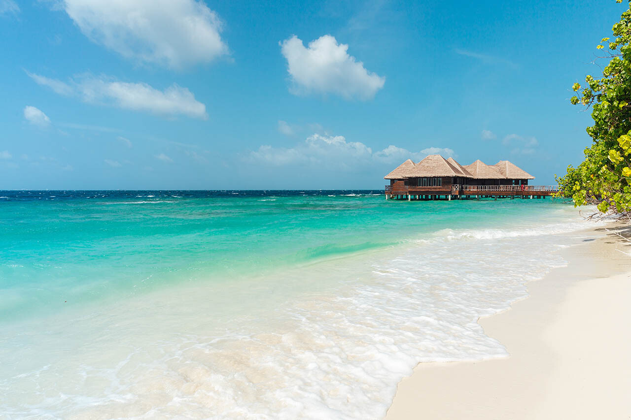 Paradise beach scene with white sand, ocean, and water bungalows, Maldives